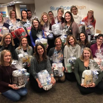 A group of Blue Ocean Brain employees posing with the patient comfort care baskets they made for cancer patients at the VCU Massey Cancer Center in Richmond, VA.