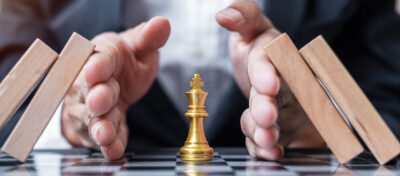 Business man hand protect Chess King figure and Stopping Falling wooden Blocks or Dominoes. Business, Risk Management, Solution, economic regression, Insurance, strategy and Interruption Concepts
